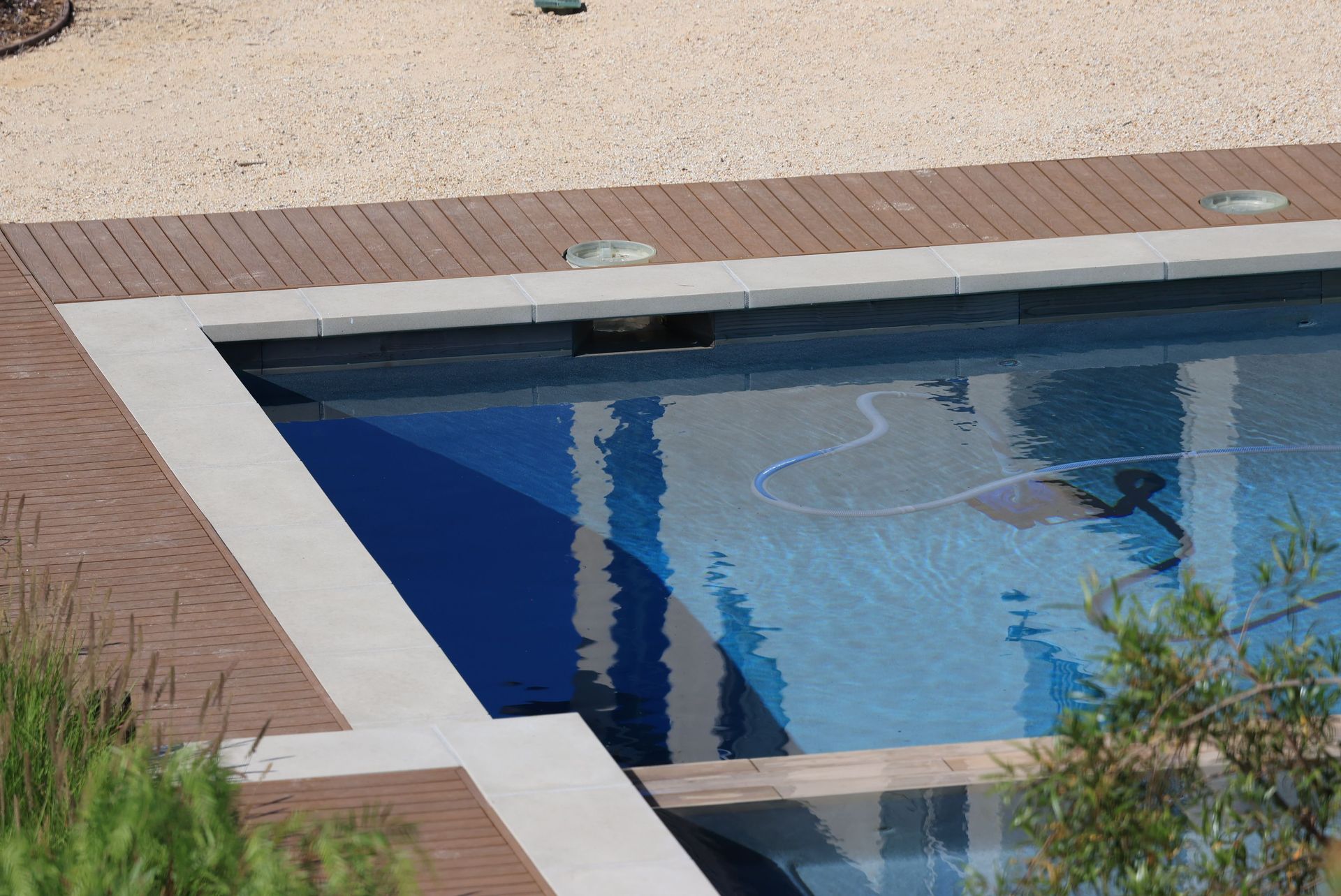 Outdoor swimming pool with blue water, white coping, and brick patio edging