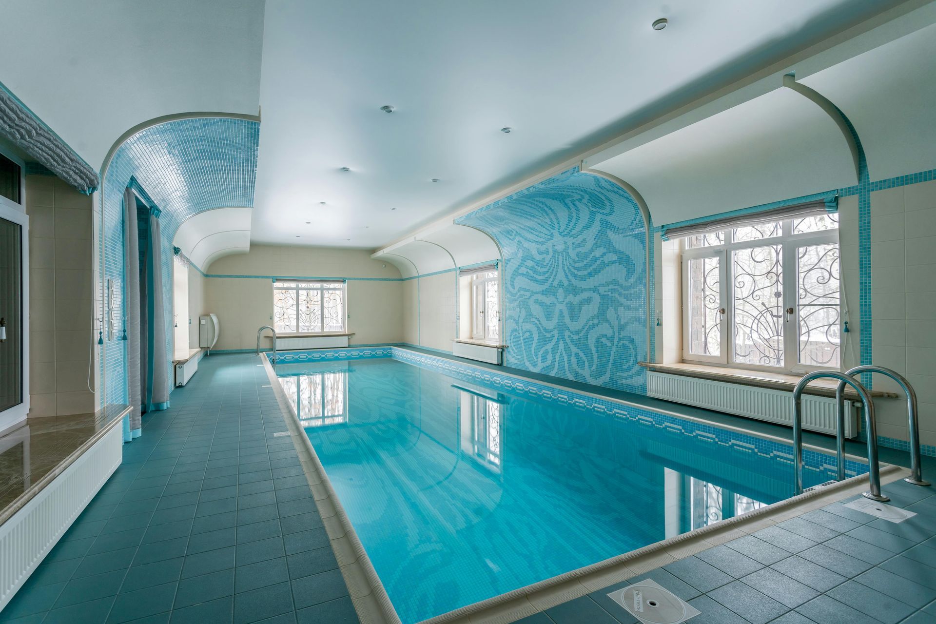 Indoor swimming pool with turquoise water, tiled walls, and a narrow lane beside the pool