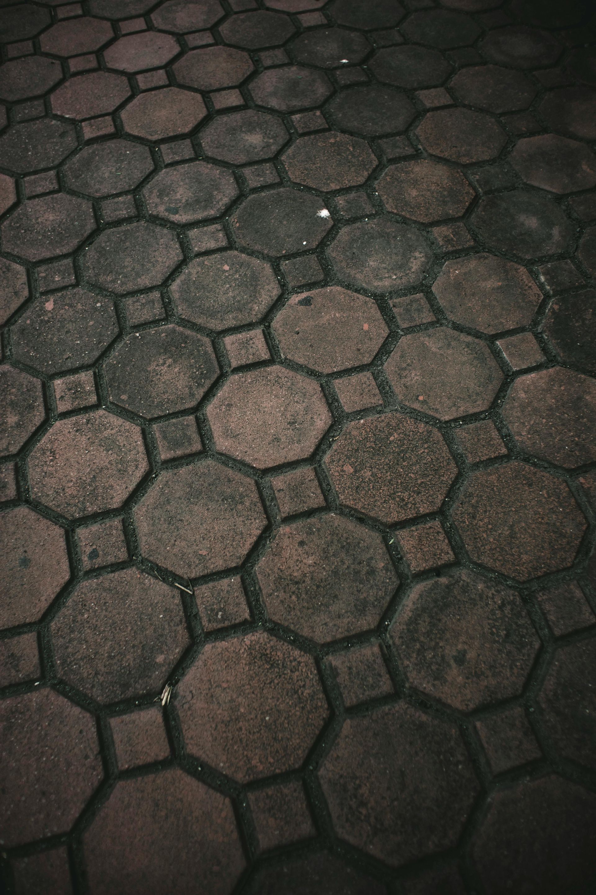 Dark hexagonal stone pavement with worn, dusty tiles, viewed from above