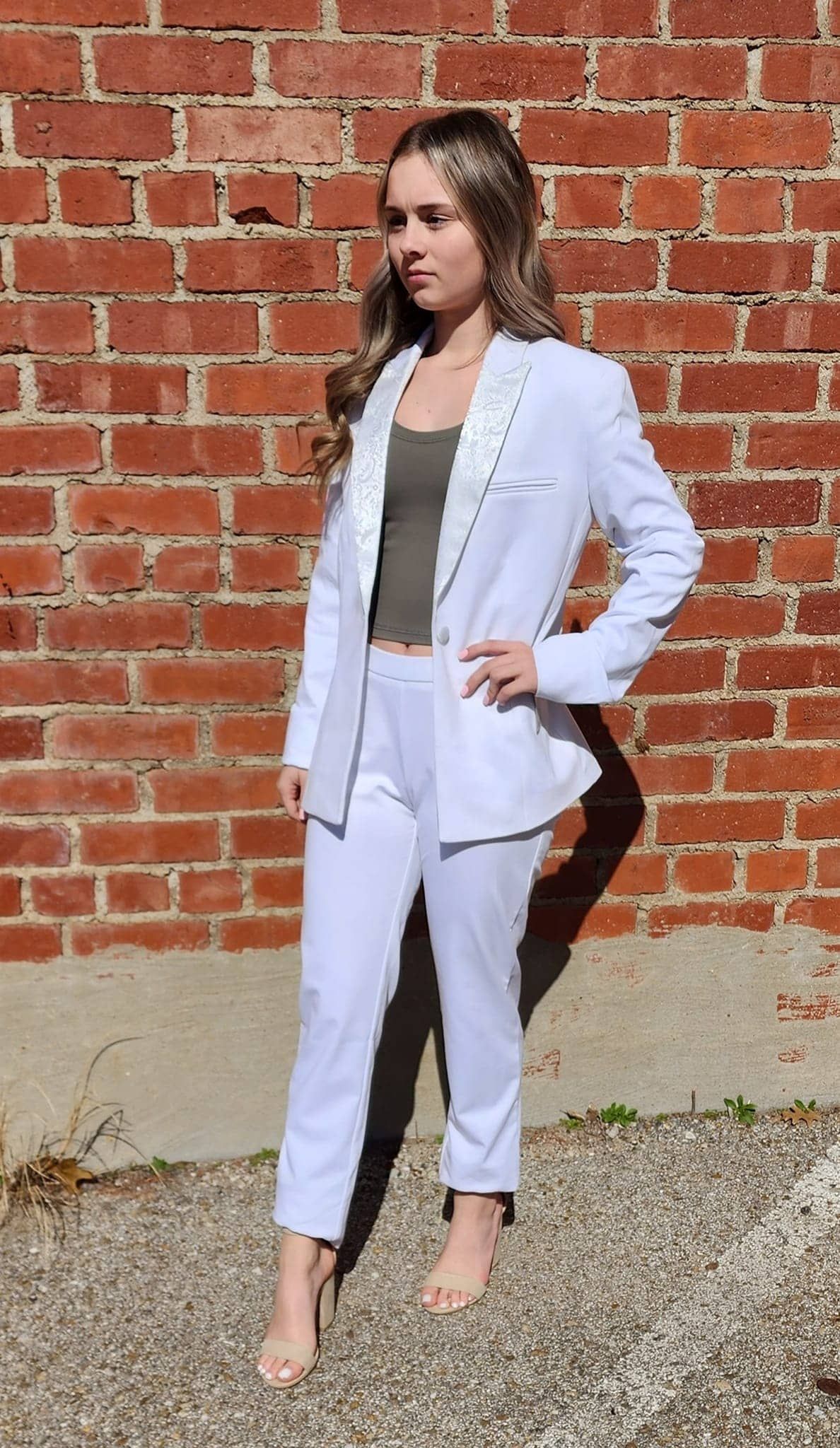 young lady standing by brick wall in rented formal wear