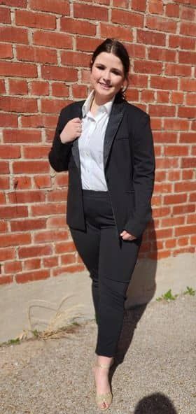 a woman in a suit is standing in front of a brick wall .