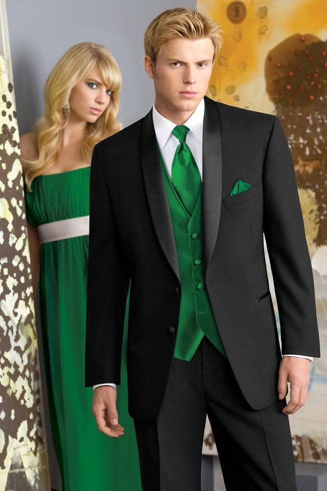 a man in a black suit and green vest is standing next to a woman in a green dress .