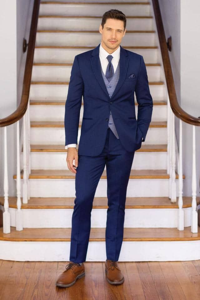 a man in a blue suit and tie is standing on a set of stairs .