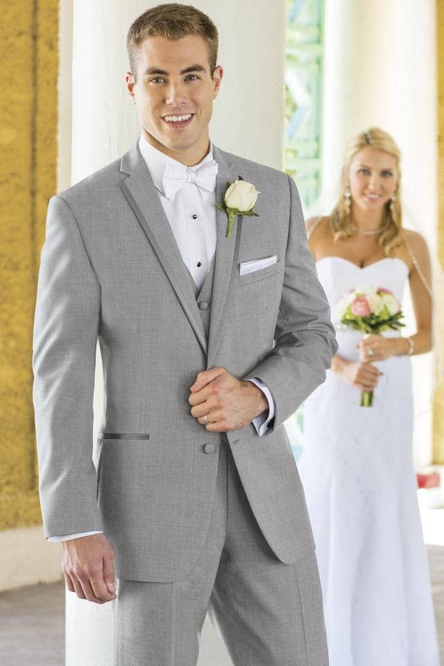 a man in a suit is standing in front of a bride and groom .
