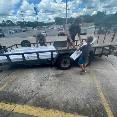 A man and a boy are pushing a trailer full of boxes.