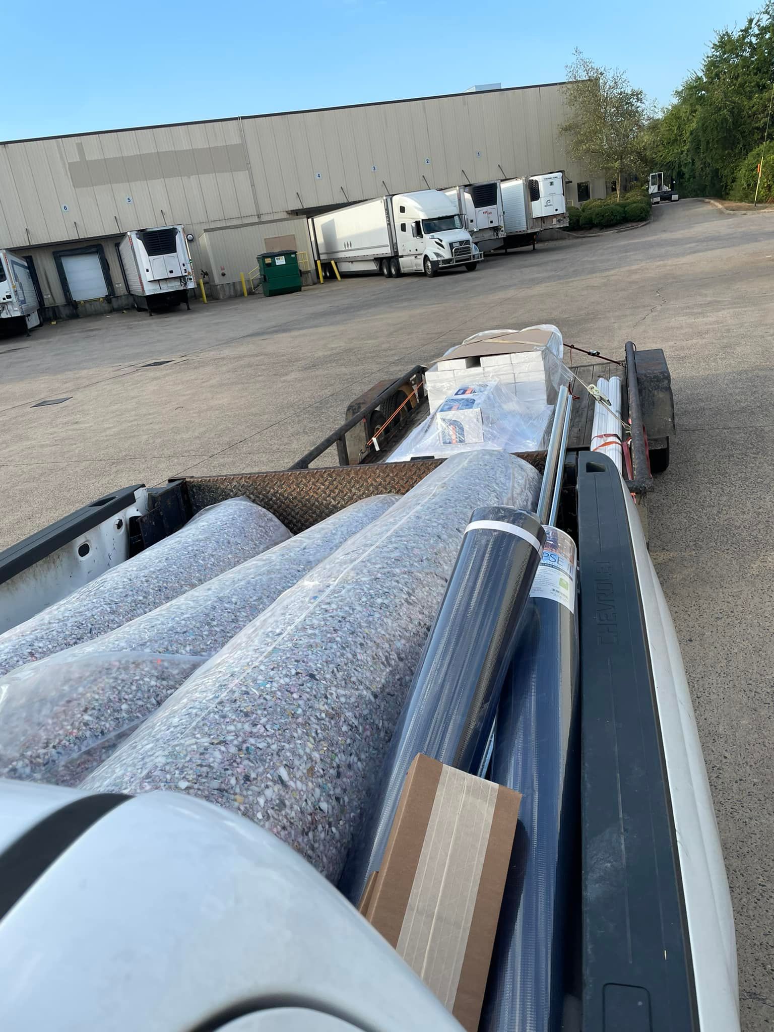 A truck is loaded with rolls of carpet in a parking lot.