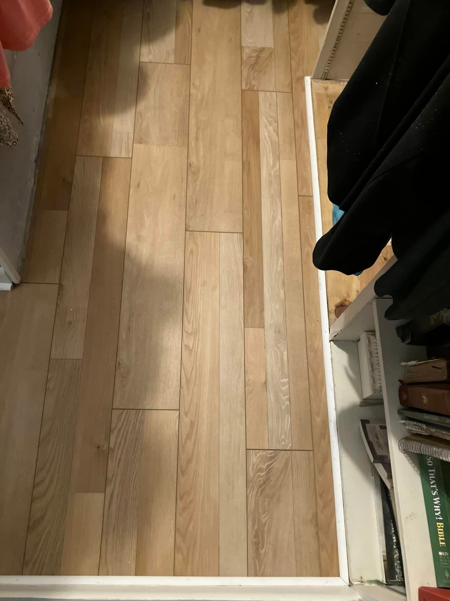 A wooden floor in a closet next to a bookshelf.
