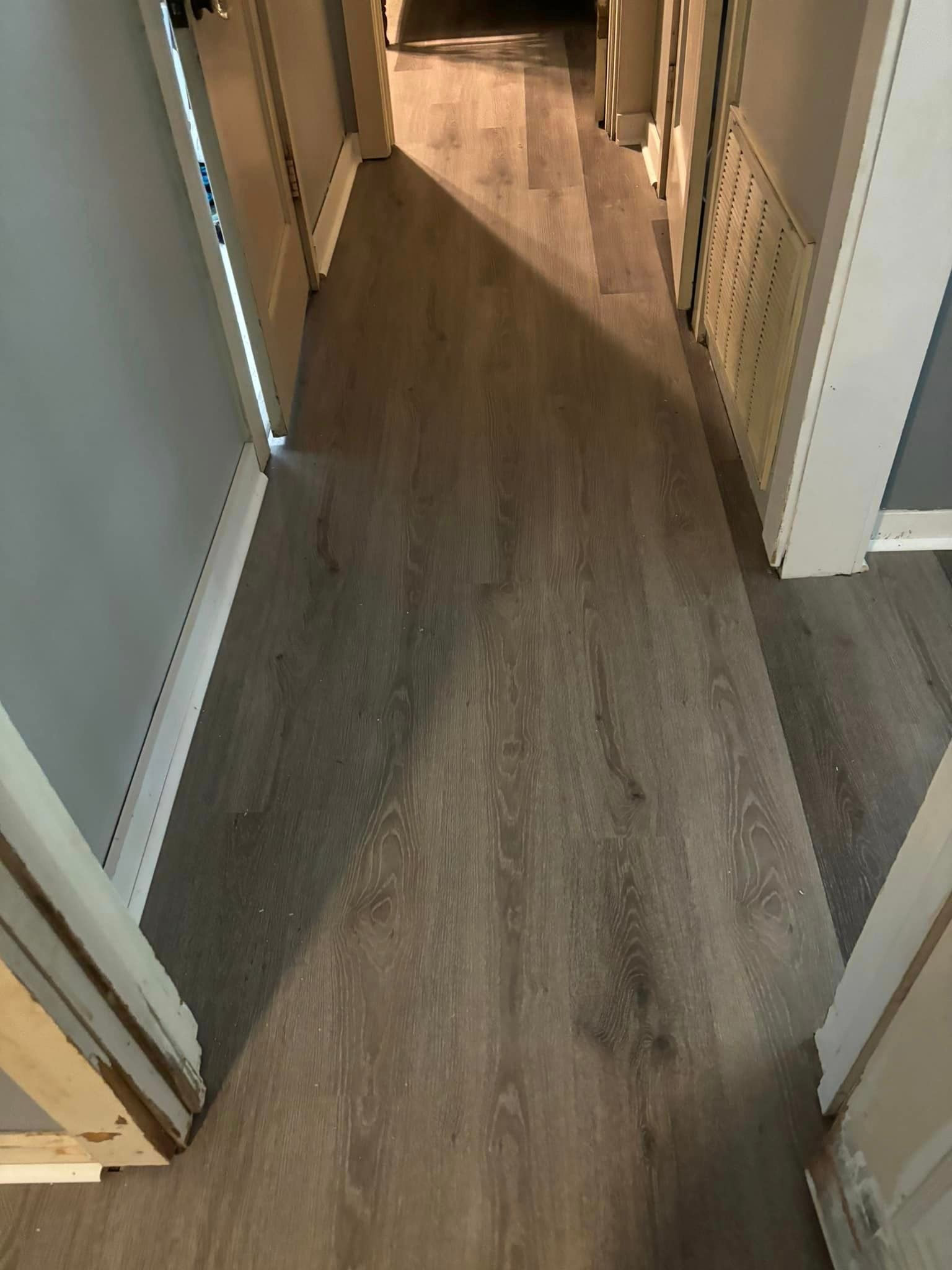 A hallway with hardwood floors between two doors.