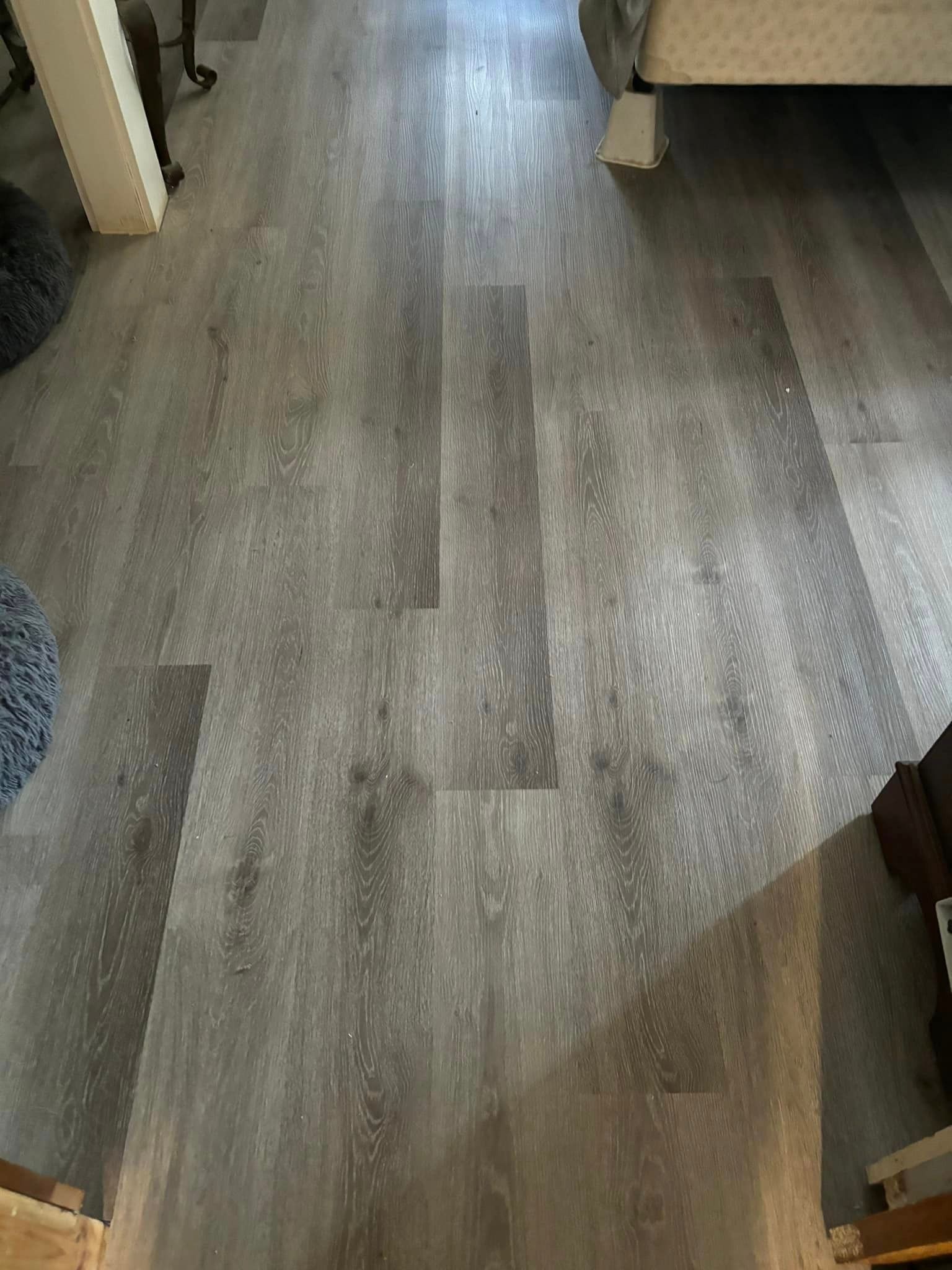 A living room with a hardwood floor and a bed.