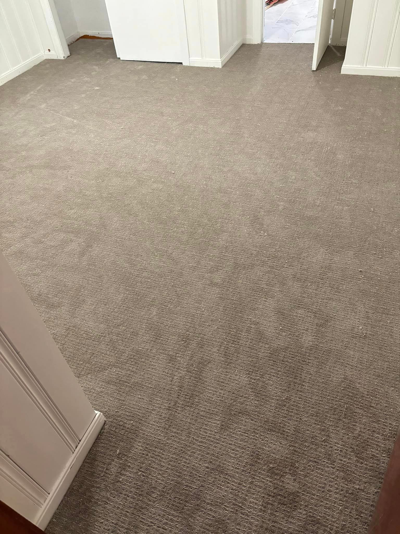 A room with a carpeted floor and a doorway leading to another room.