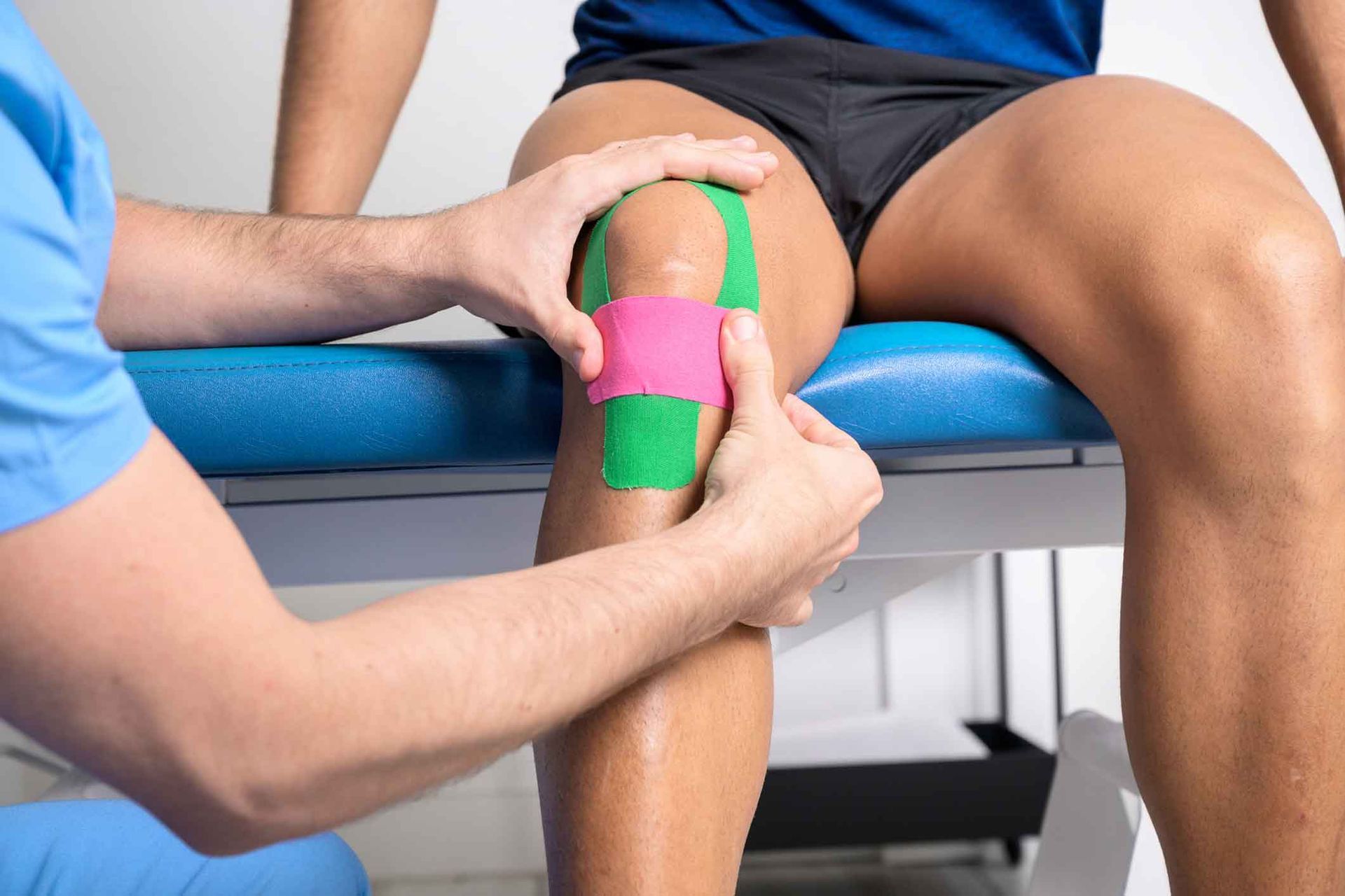 Knee pain treatment with physiotherapist applying kinesiology tape for injury support and muscle recovery.