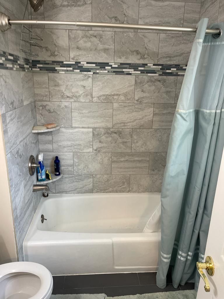 A bathroom with a bathtub , toilet and shower curtain.