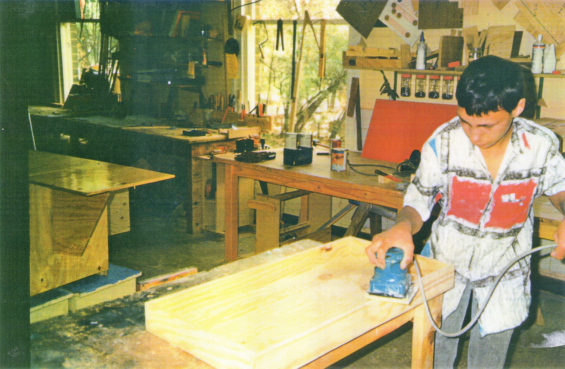 A man is sanding a piece of wood in a workshop