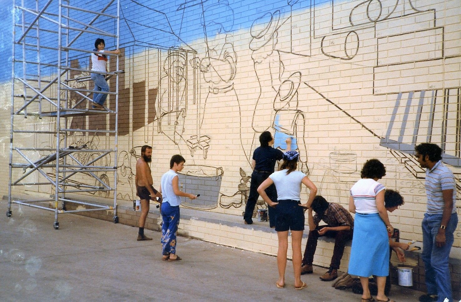 A group of people are working on a mural on a wall