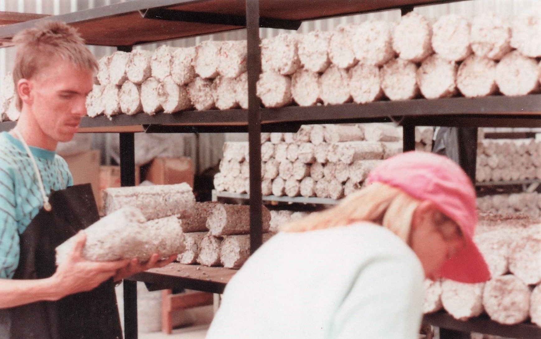 A man and a woman are looking at mushrooms in a warehouse