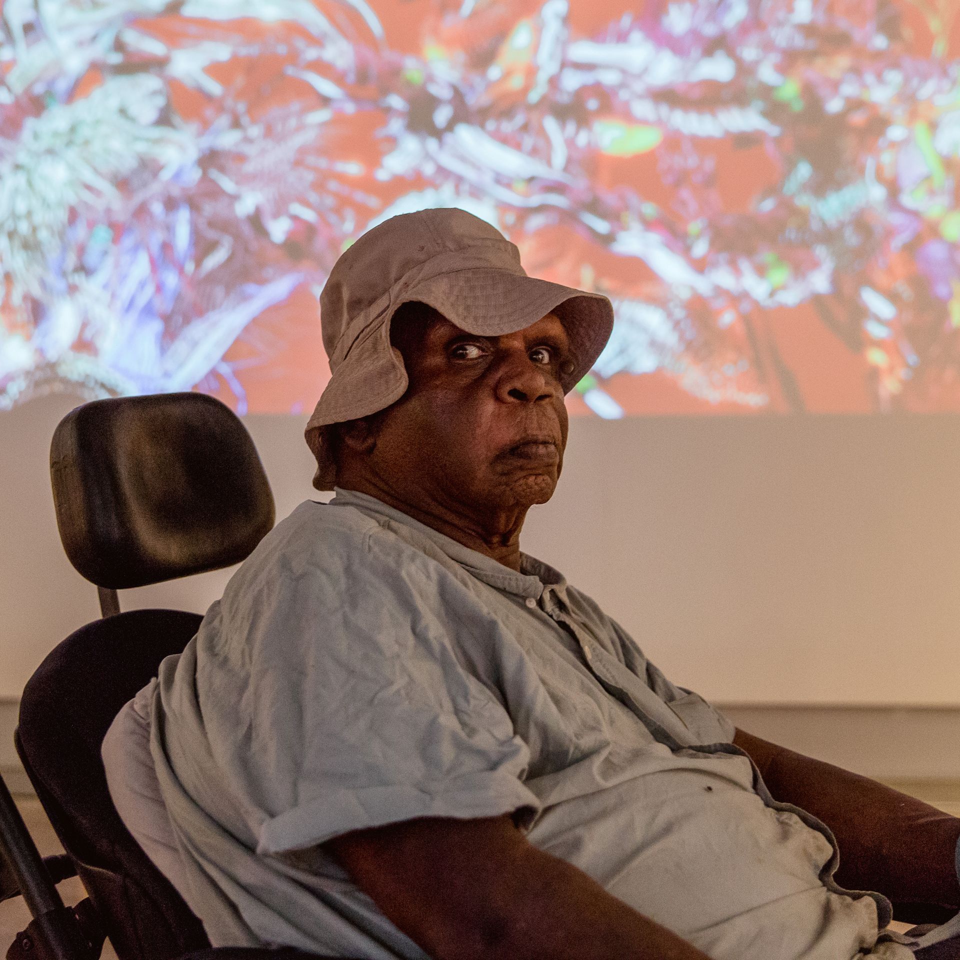 A man wearing a hat is sitting in a wheelchair