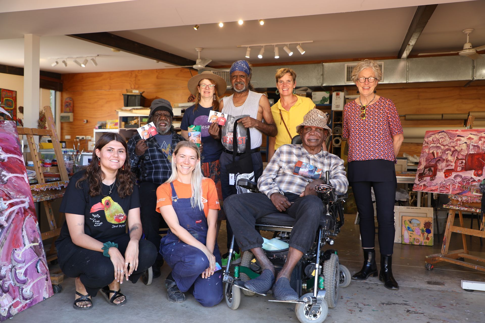 A man is smiling while holding a piece of paper in front of a mailbox.