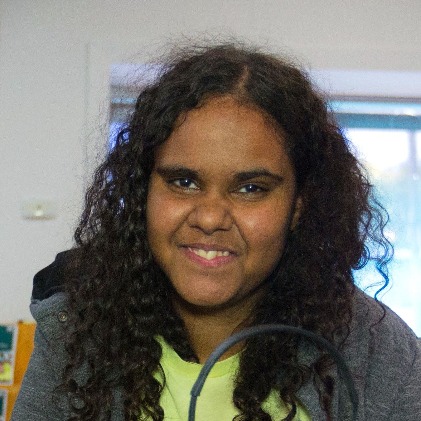 A young girl with curly hair is smiling for the camera.