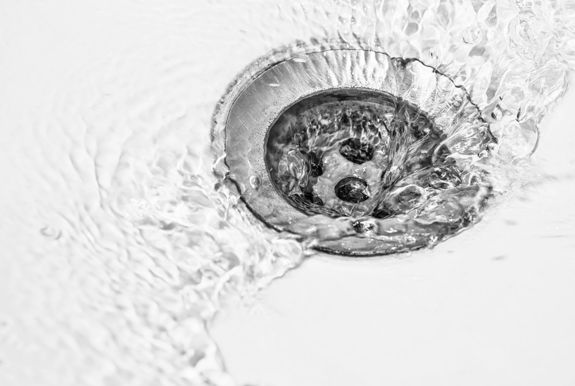 Water flowing into a drain in a white sink.
