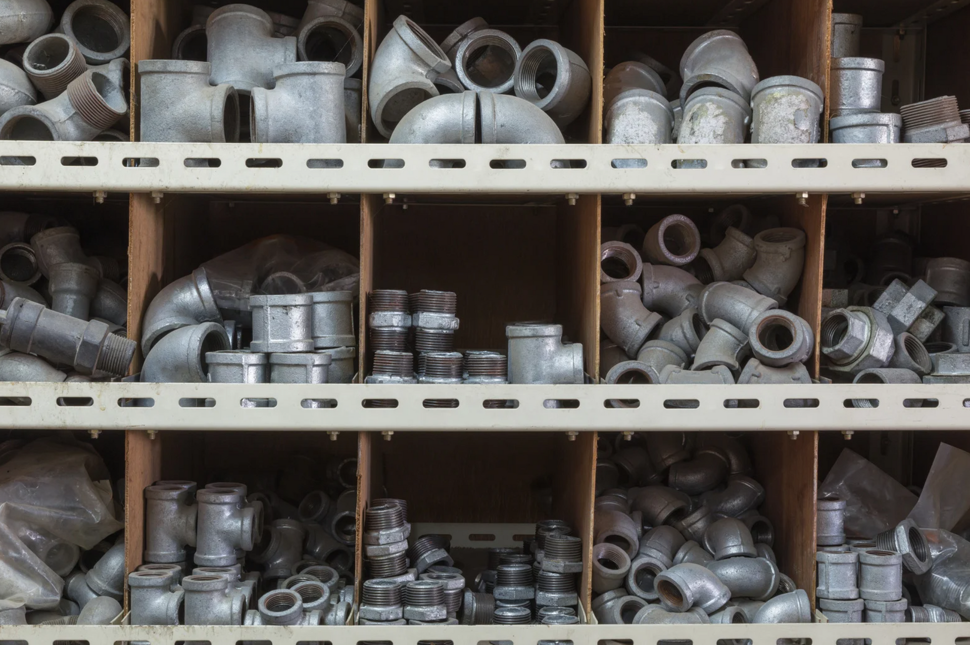 Metal plumbing fittings organized in a storage rack.
