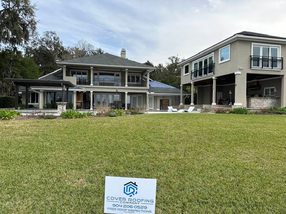 Two-story houses with green lawns. A roofing sign is in the foreground.