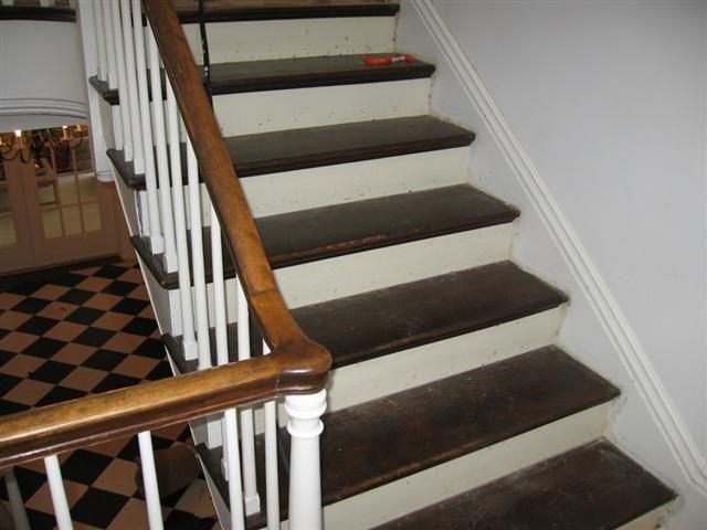 Indoor staircase with white spindles, brown carpeted steps, and a wooden banister