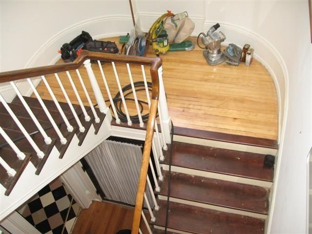 Staircase landing with wooden floor and scattered tools, seen from above.