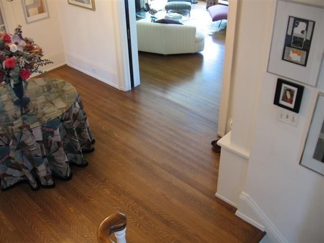 Living room hallway with wood floors, round table with floral cloth, and white sofa visible through doorway