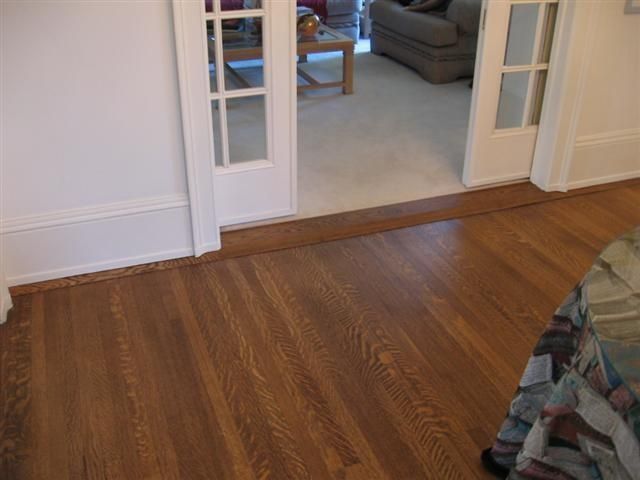 Wood floor leading into a carpeted room through open glass doors