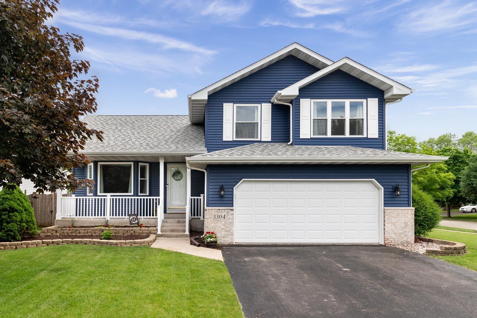A blue house with a white garage door is for sale.
