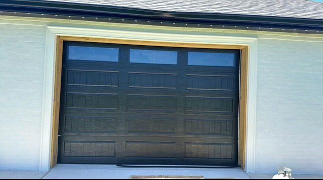 A black garage door is open on a white house