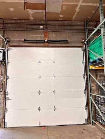 A white garage door is open in a warehouse.