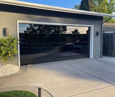 A house with a black garage door and a car parked in front of it.
