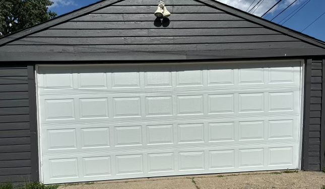 A white garage door is sitting on top of a black garage.