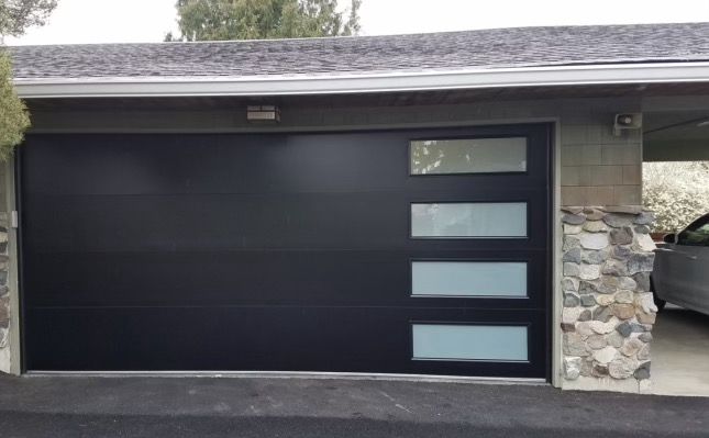 A car is parked in a garage with a black garage door.