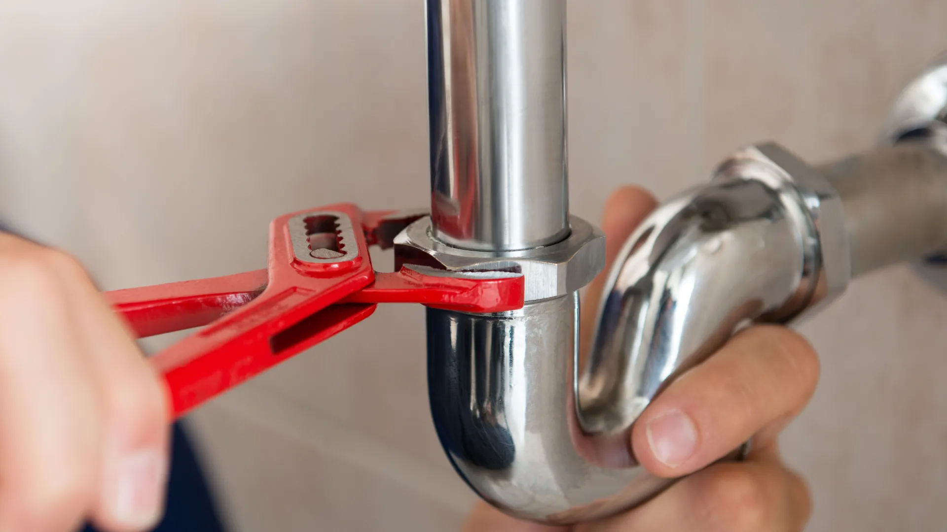 A plumber is fixing a pipe with a wrench.