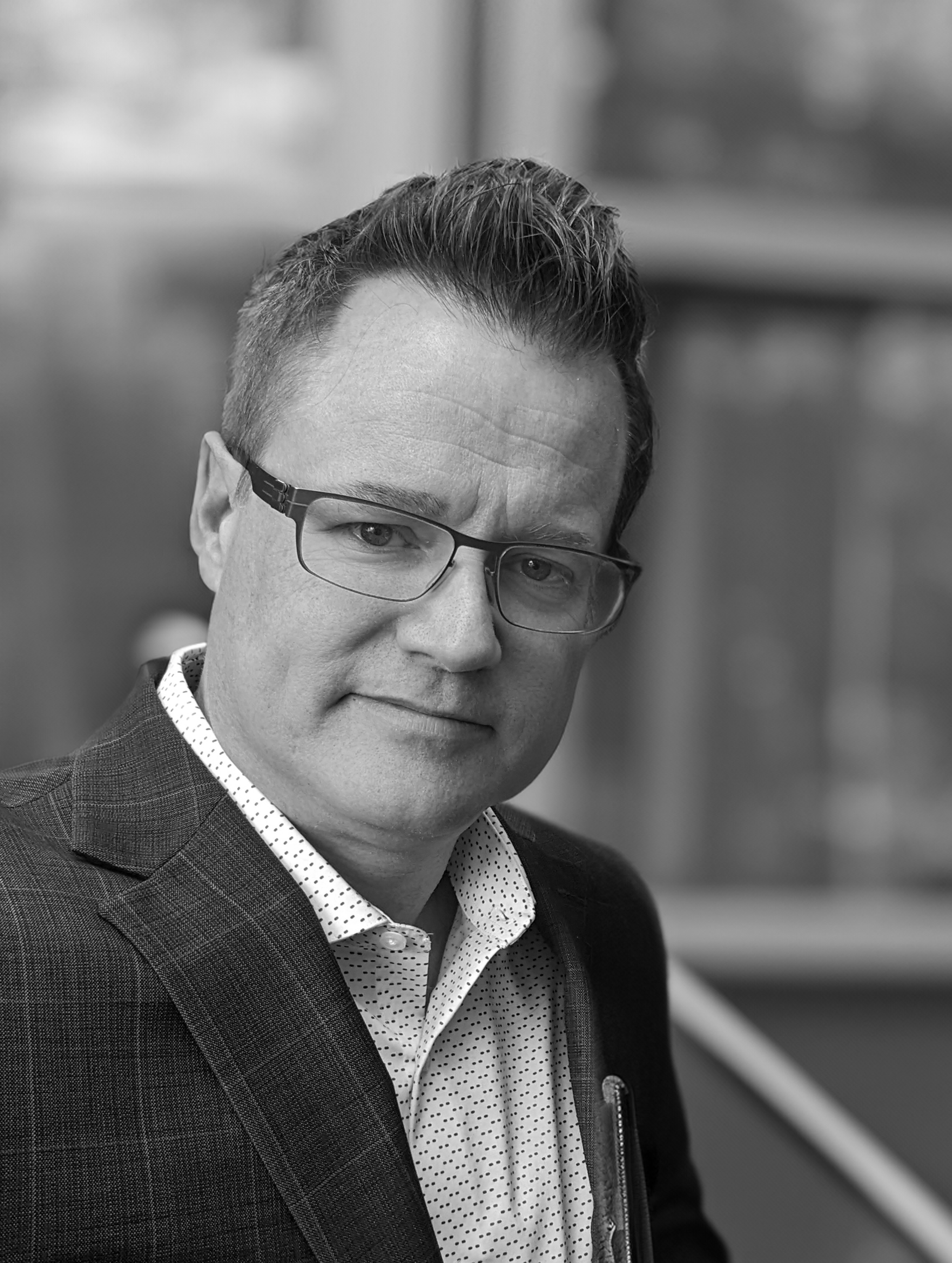 A black and white photo of a man wearing glasses and a suit.