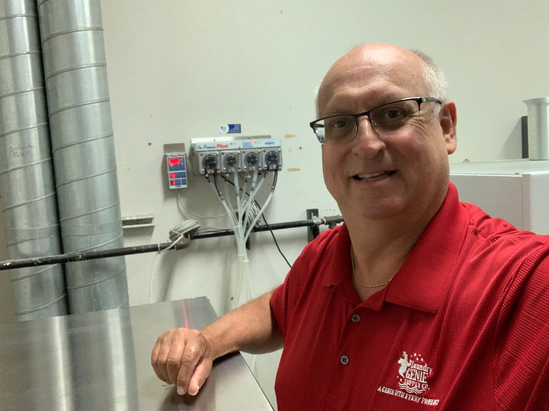 A man wearing glasses and a red shirt is sitting at a table.