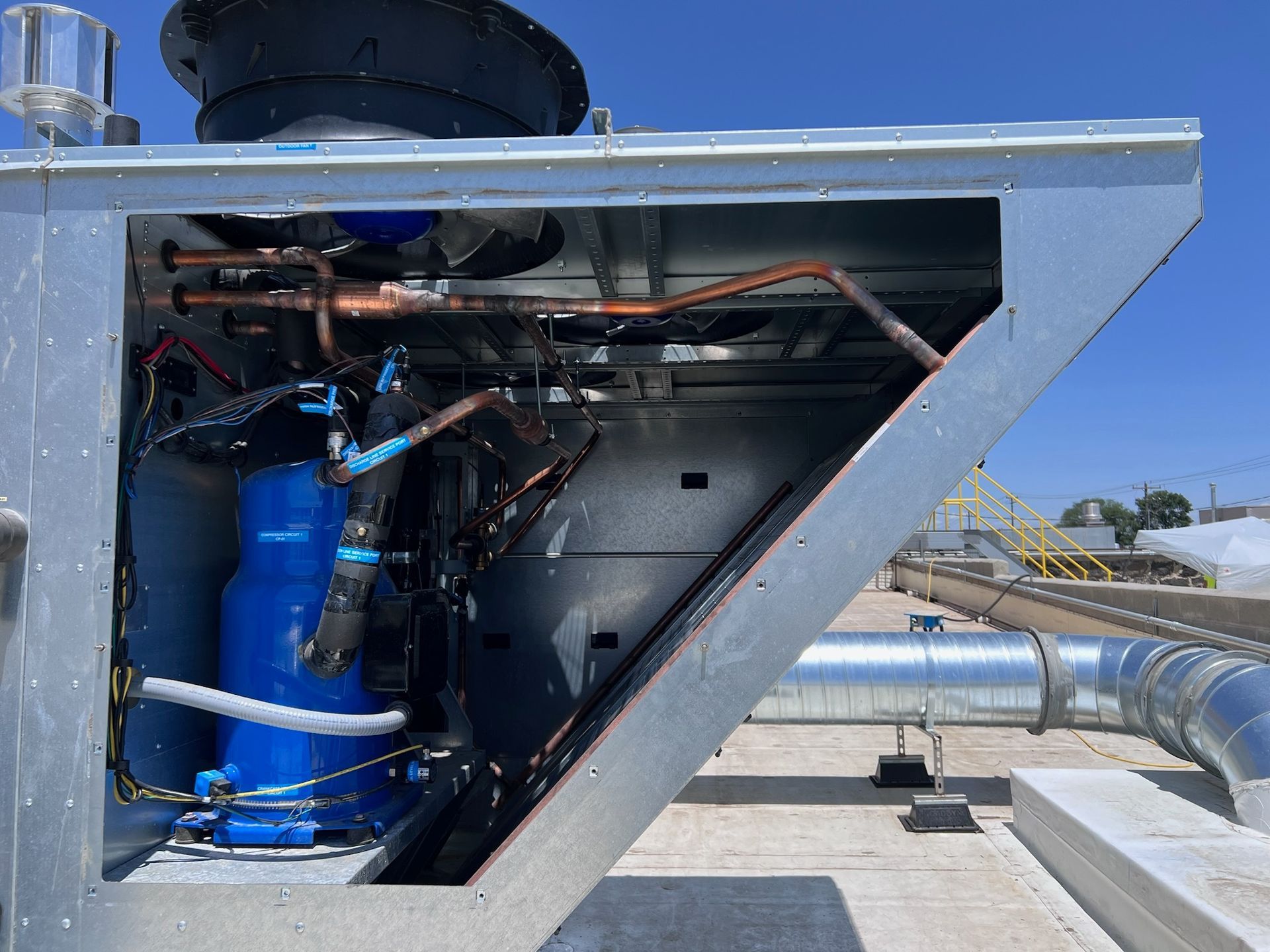 A man is sitting on the floor fixing an air conditioner.