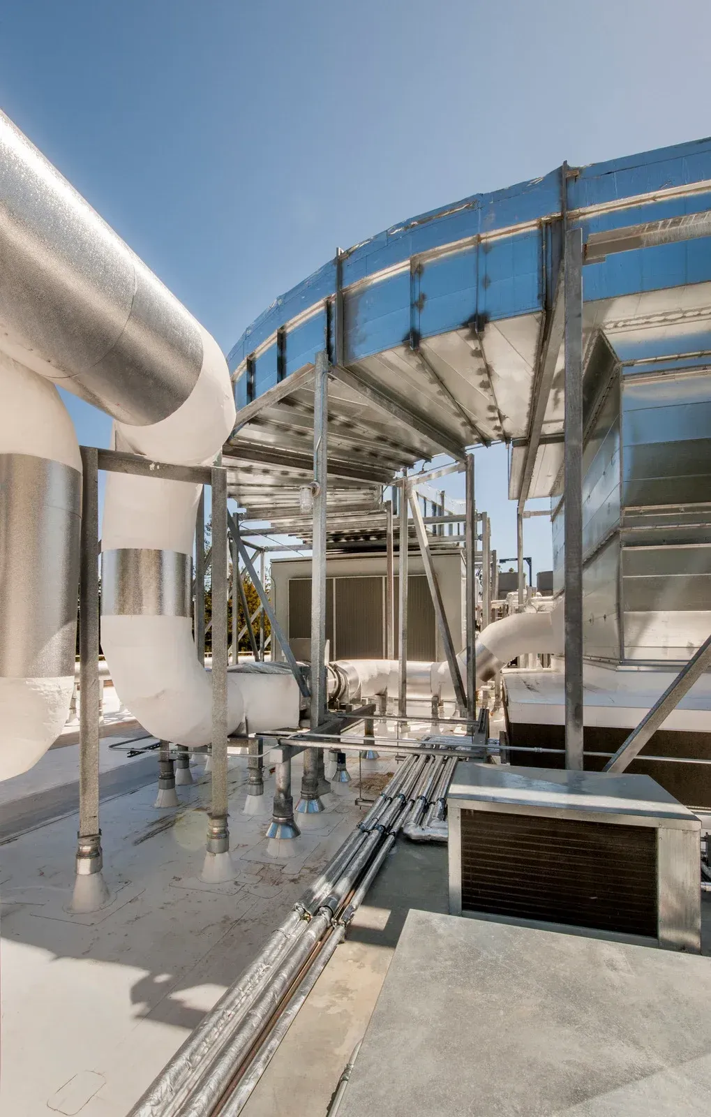 A rooftop of a building with pipes and a blue sky in the background.