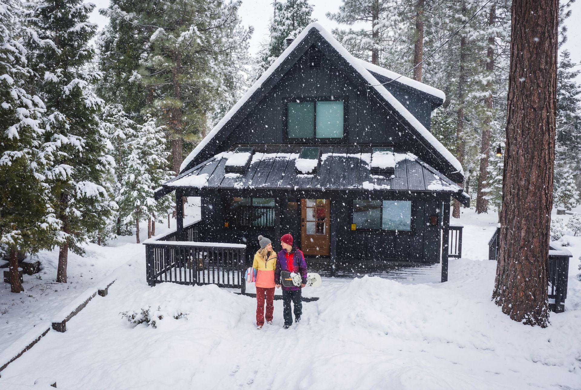 Snowy cabin with two people standing outside in winter woods