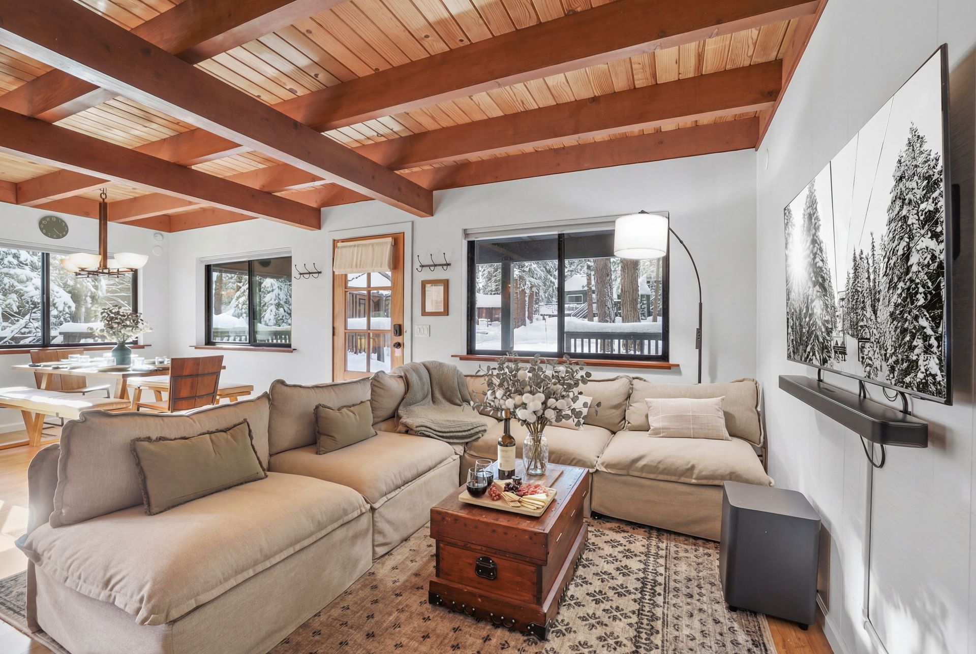 Bright living room with beige sectional, wood-beamed ceiling, fireplace, and large wall art