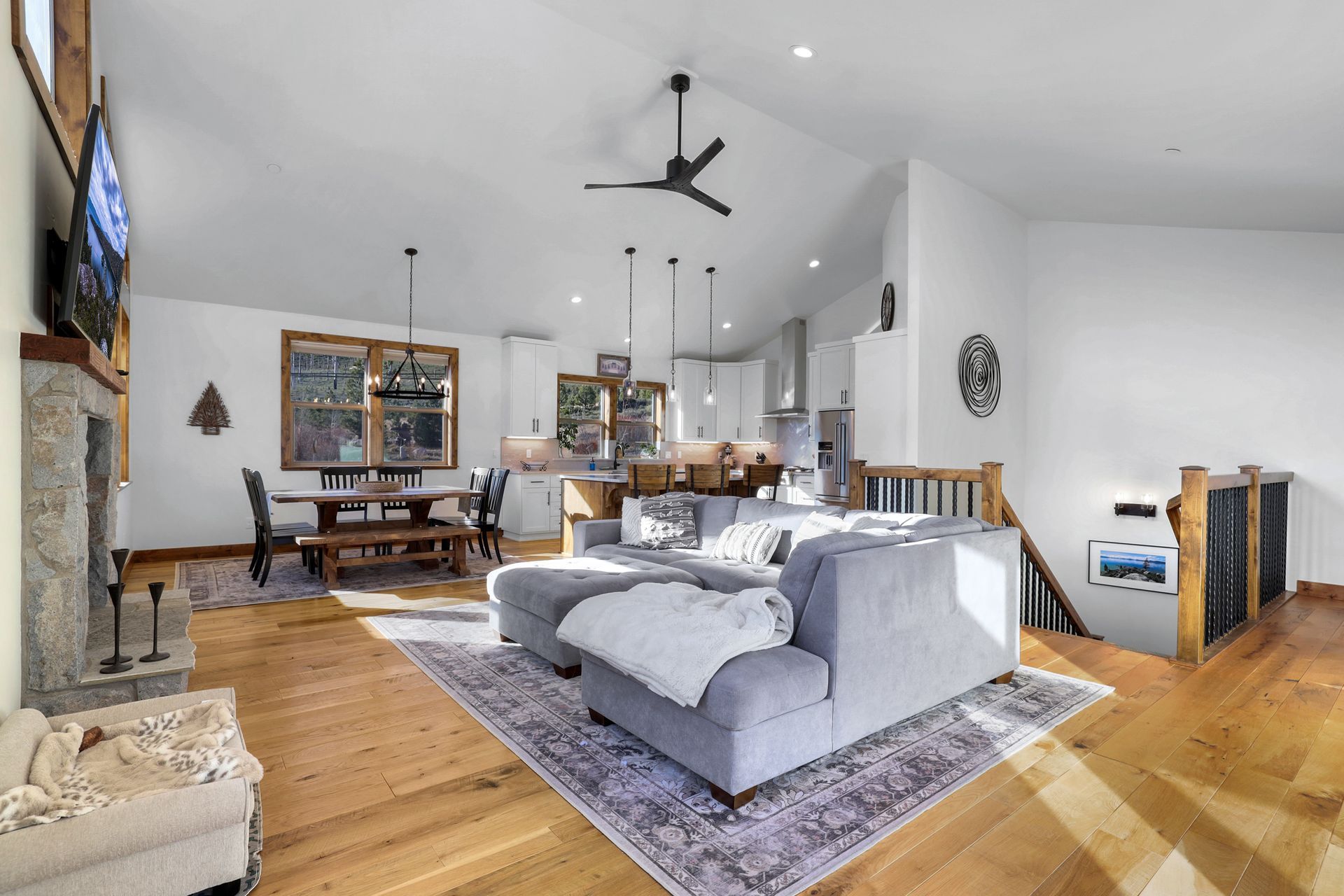 Spacious modern living room with gray sectional, rug, wood floors, dining area, and kitchen beyond