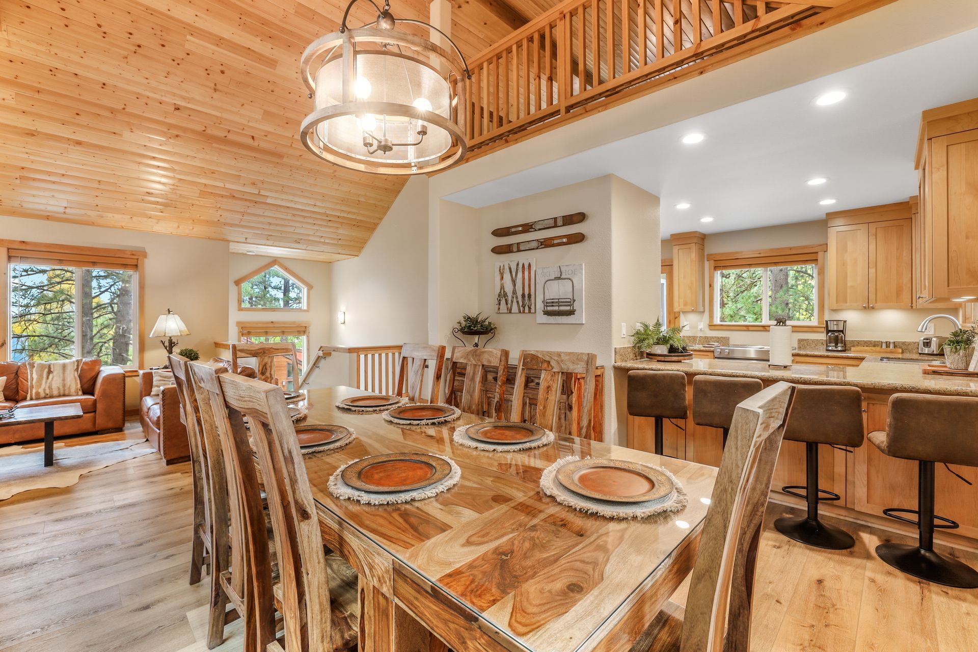 Bright rustic open-concept kitchen and dining room with wood beams, stone accents, and a large wooden table
