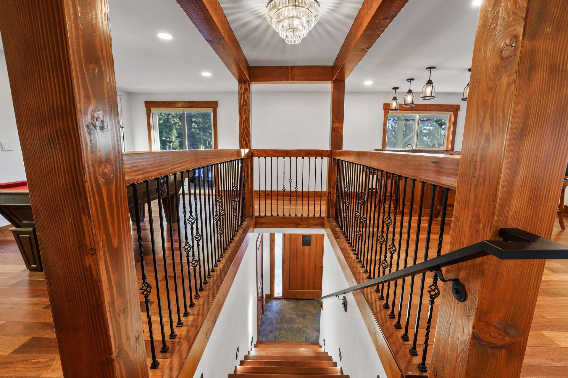 Staircase landing with dark wood railings, white walls, and a chandelier overhead