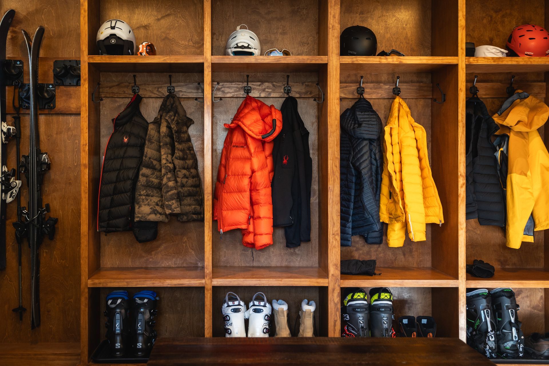 Wooden locker cubbies with winter jackets, helmets, and boots neatly arranged