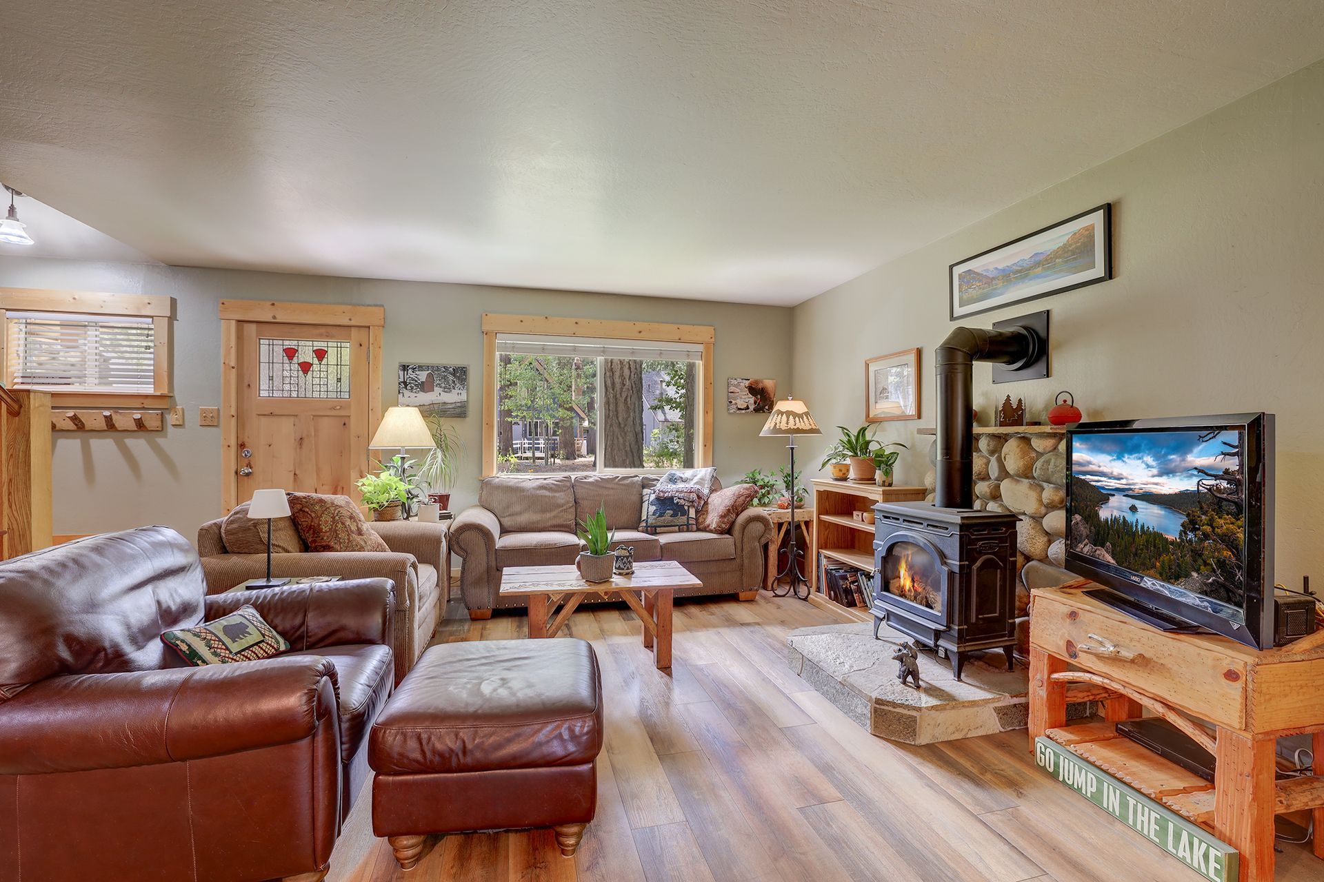 Cozy living room with leather sofa, armchairs, fireplace, and TV by the window