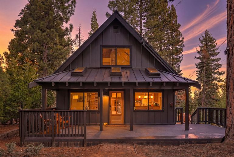Wooden dock extending into clear turquoise water towards a row of houses and trees.