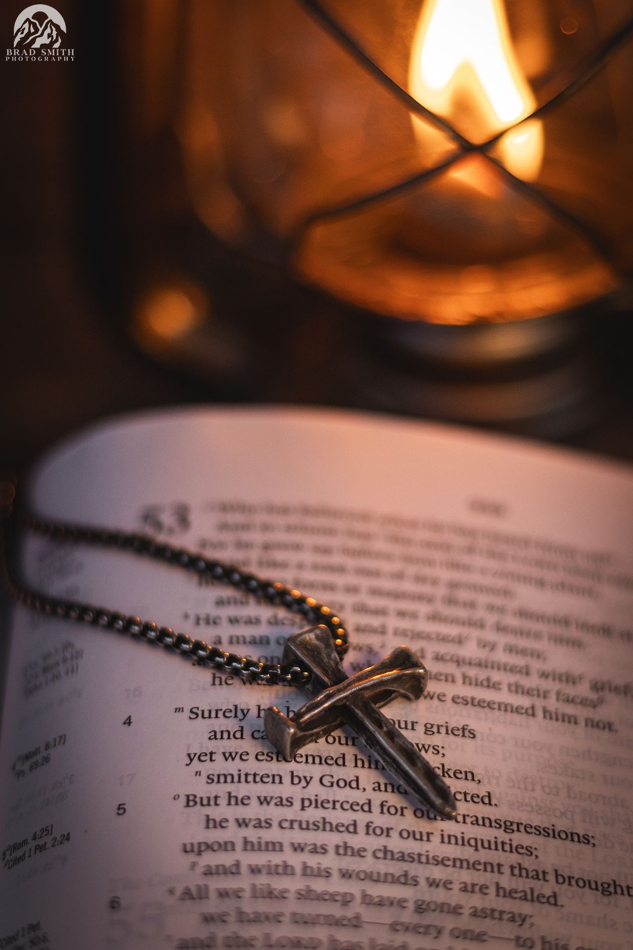 Open Bible with rosary beads beside a glowing candle in warm, dim light
