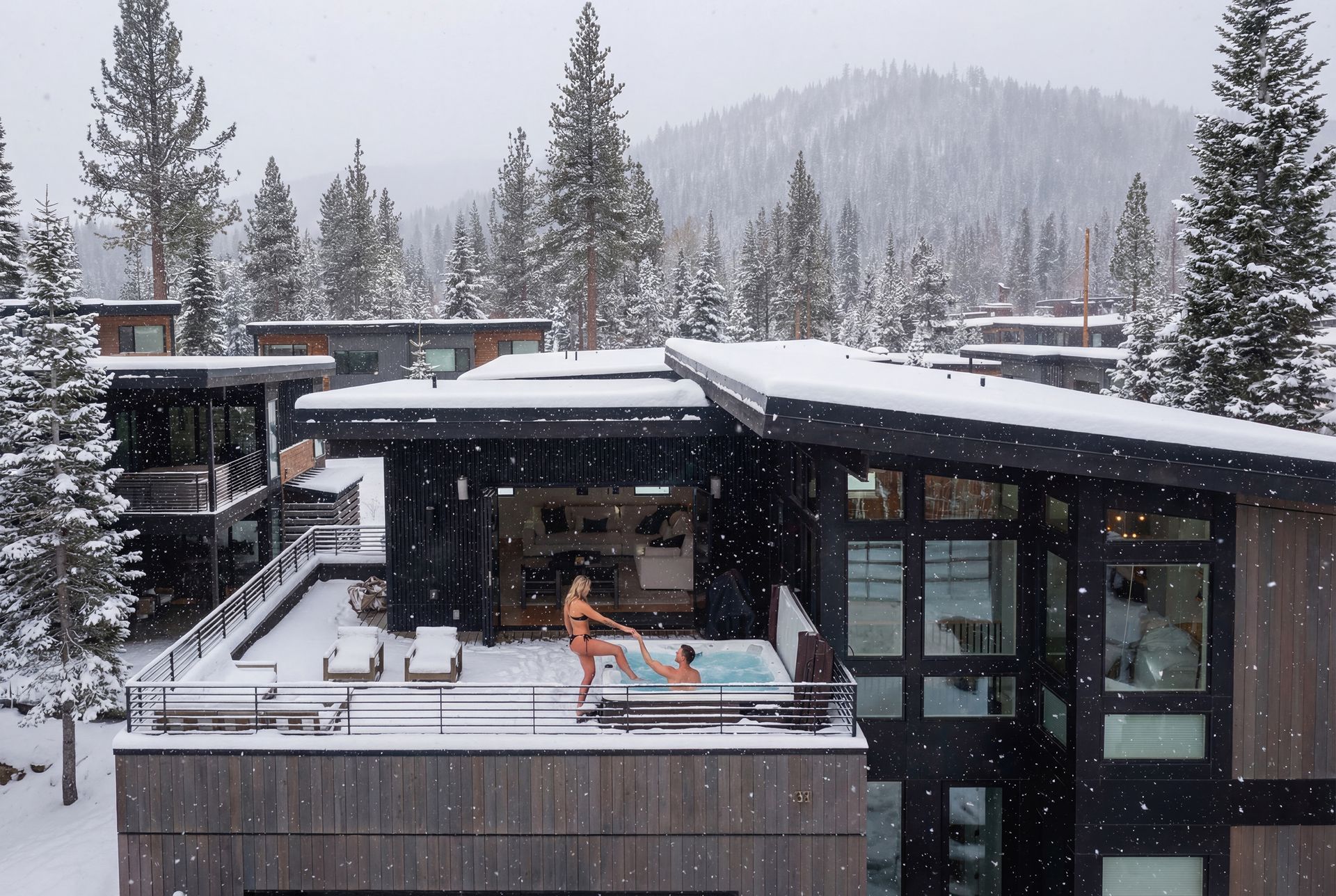 Snowy mountain resort with a rooftop hot tub and people relaxing outdoors